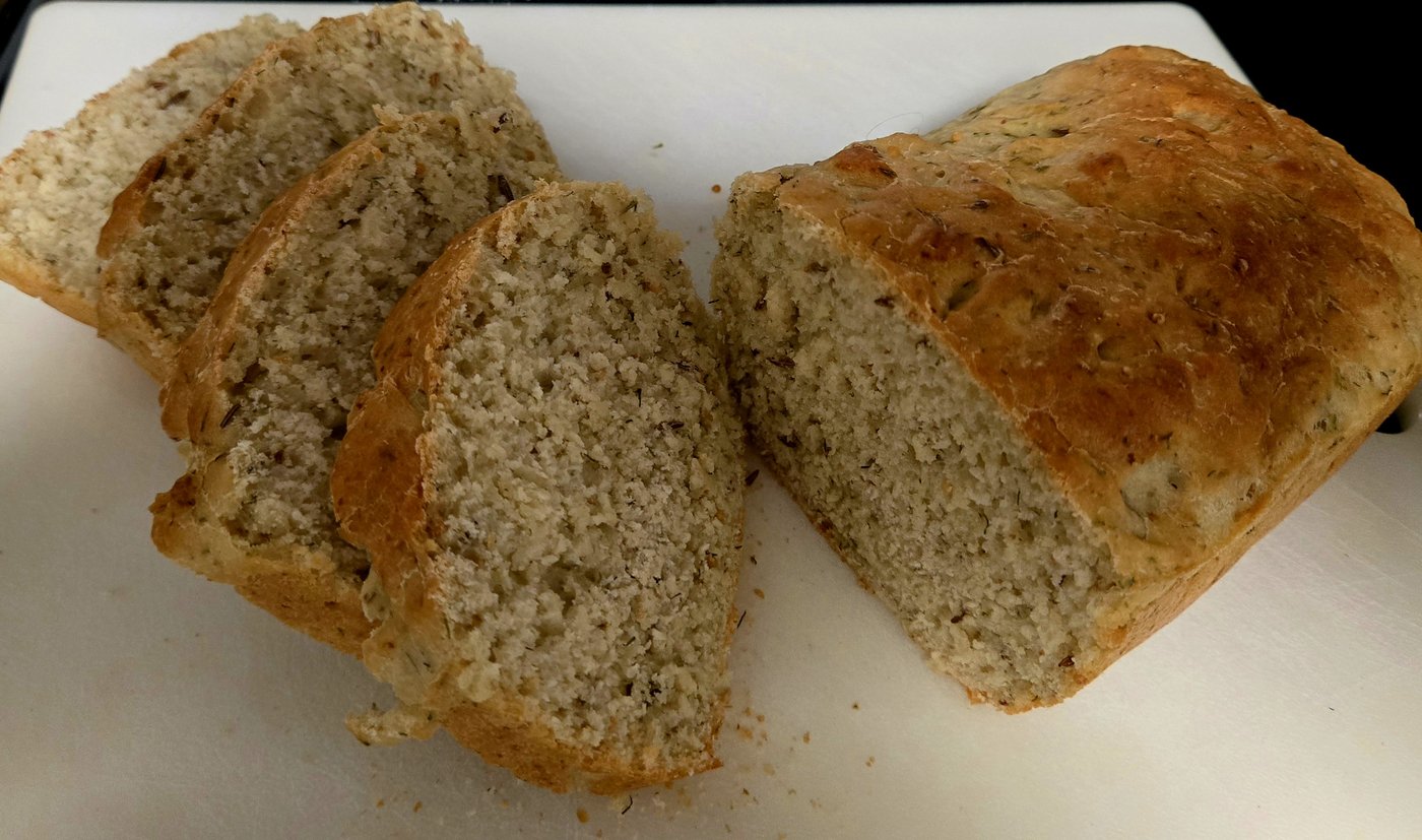 A loaf of dill mustard bread, sliced on a board